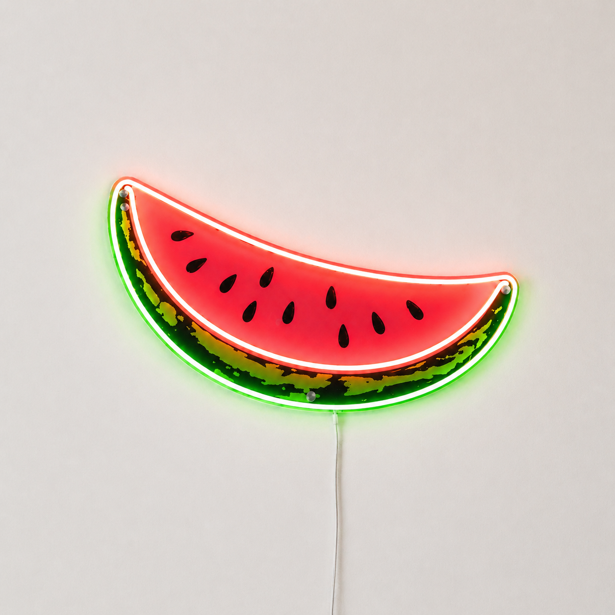 Néon LED Slice en forme de tranche de pastèque rouge avec écorce verte et pépins noirs sur mur blanc